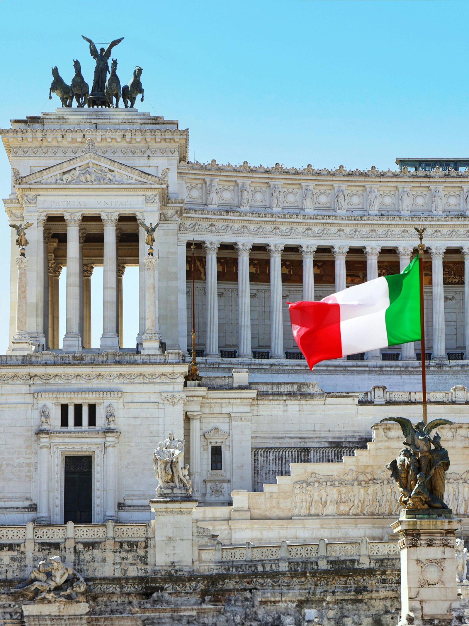 Vittoriano Monument in Rome with the Italian flag waving in the foreground.